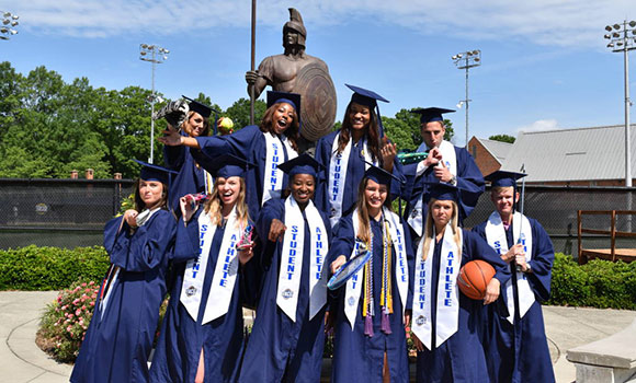 Student-athletes pose in their graduation caps and gowns